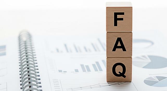 Wooden blocks spelling FAQ resting on a spiral notebook with financial charts symbolizing information and support in a business setting conveying clarity and helpfulness photo