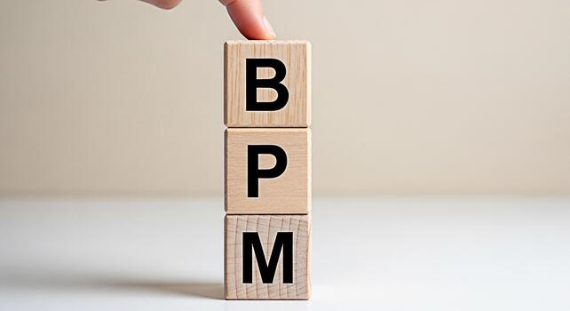 Conceptual shot of a finger touching wooden blocks spelling BPM in a bright studio representing business process management and workflow optimization for improved efficiency and strategic planning photo