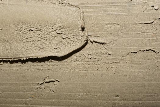 On a smooth, damp cement or plaster surface, wide, barely noticeable trowel marks create a rough texture, a background in construction and renovation photo