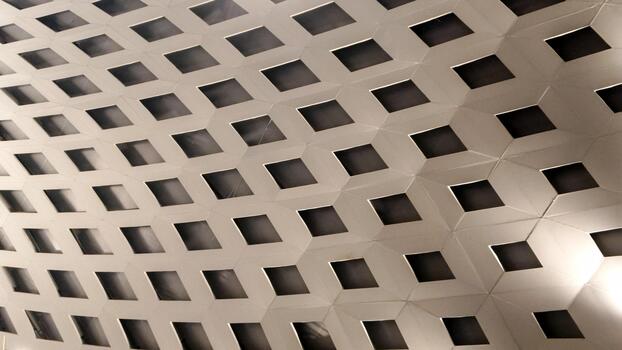 Abstract geometric pattern of interconnected hexagonal shapes with square cutouts, creating a textured surface with depth. Ideal for modern design, backgrounds, technology, or architectural detail photo