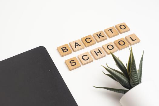 Back to school written in wooden blocks on a white background. The blocks are arranged in such a way as to form the words Back to School between the book objects and flowers as decoration photo