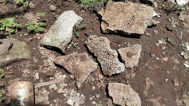 A close-up photo of a rough rock on dusty ground, in direct sunlight, is relevant for an environmental classification AI dataset.