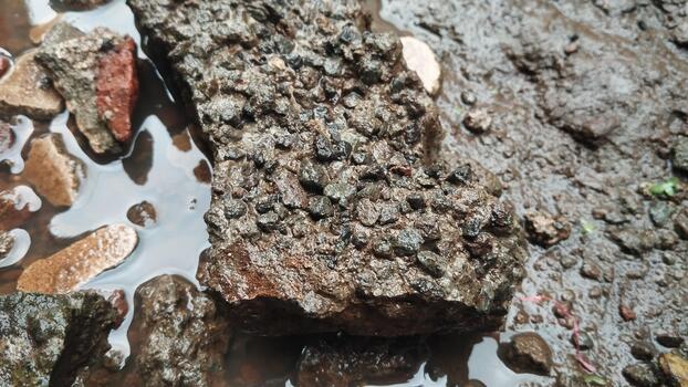 Detailed photo of a natural stone object with a rough texture and rain. Natural light in an open environment. Suitable for AI datasets of natural environment visualization.