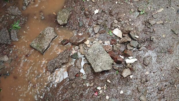 High angle shot of muddy ground and broken rocks with small puddles, ideal for AI data classification of wet environmental conditions. photo