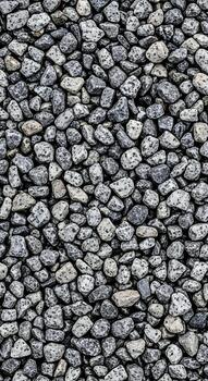 A closeup overhead view of a pile of small, rough, gray and white stones, creating a textured background pattern photo