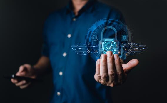 man in a blue shirt holds a smartphone while a glowing holographic shield with a padlock and circuit design floats above his hand, symbolizing cybersecurity, data protection, and information security. photo