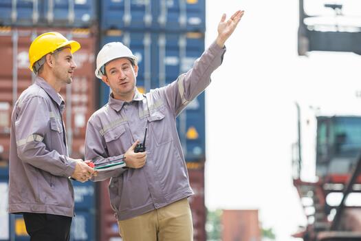 Engineers and foremen discussing cargo logistics and operation plan at a container port, Caucasian supervisors pointing and planning workflow in a busy shipping yard with containers photo