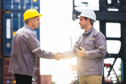 Engineers Man Shaking Hands at Shipping Container Yard, Diverse Engineers Working Together in Container Terminal, Industrial Professionals Seal a Deal at Port photo