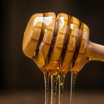 Close-up of a golden honey drizzle from a dipper against a dark rustic background, sticky texture photo