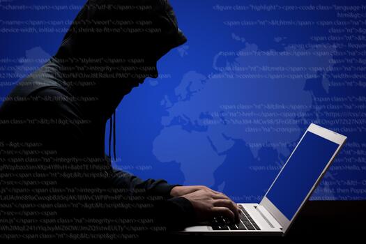 Dangerous male hacker in black hoody works hard on solving online password code on laptop computer, keyboards information, tries to break system, poses sideways against dark binary streams background photo