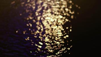 d'oro bokeh scintillante su un' acqua superficie a notte, la creazione di un' caldo e romantico atmosfera, calma emotivo scene, Perfetto per astratto arte o elegante sfondo uso video