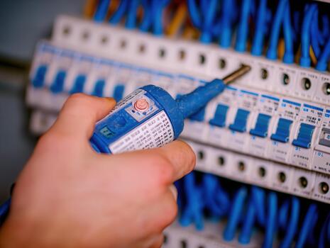 Electrician testing circuit breakers in a residential building during the day to ensure proper electrical function and safety photo