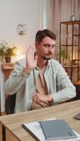 ung man frilansare med allvarlig uttryck håller på med sluta gest med både händer på Hem kontor skrivbord, varning av Avsluta, förbjuden tillgång, minskande kommunikation, och kropp språk fara. vertikal. video