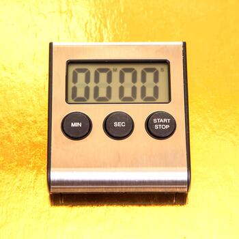 Close-up of a modern silver digital timer showing 00 00 against a vibrant yellow surface. Includes MIN, SEC, START, and STOP buttons. Perfect for culinary or productivity use. photo