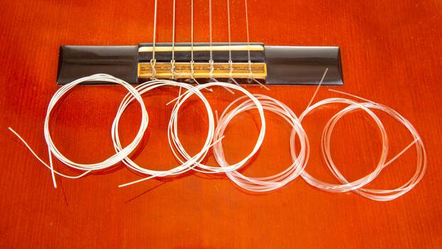 un rojo guitarra puente con recién equipado instrumentos de cuerda y un arrollado paquete de extra instrumentos de cuerda, capturado en un de cerca, enfatizando musical instrumento mantenimiento. foto