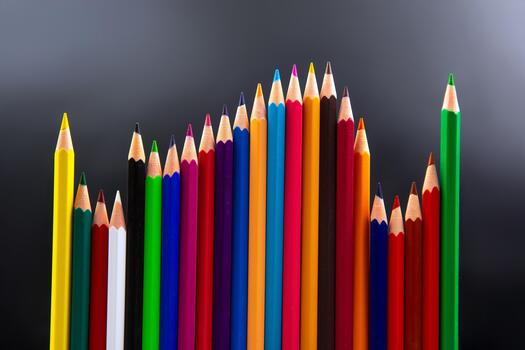 spectrum of colored pencils, from red to blue, arranged in a rising and falling pattern against a gradient gray background. Ideal for school supplies, art, and creative concepts. photo
