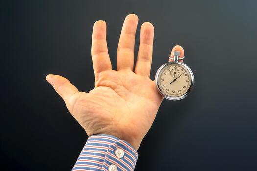 The hand with a mechanical analog stopwatch on a dark background. Time part precision. Measurement of the speed interval photo