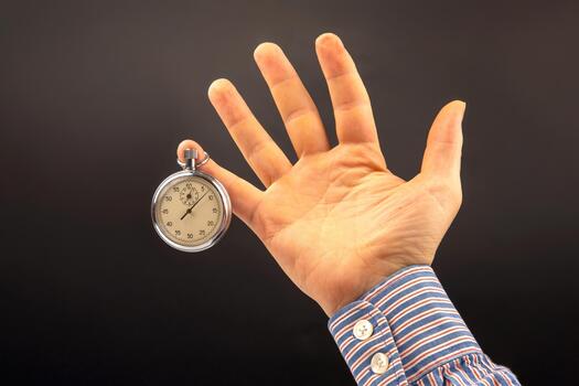 hand with a mechanical analog stopwatch on a dark background. Time part precision. Measurement of the speed interval photo