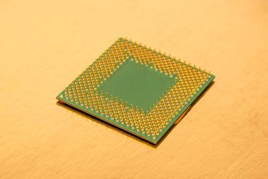 Microprocessor with gold pins resting on a smooth surface in warm lighting photo
