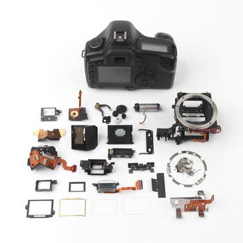 Disassembled camera components laid out on a surface in a workshop setting photo