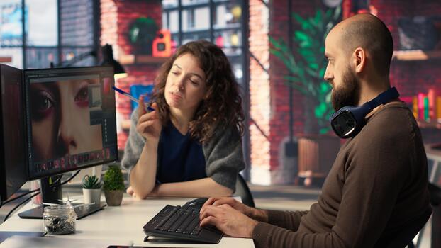 Man and woman creative team using AI to generate image models, operating editing software to enhance digital materials and create quality content. AI assistant with photo retouching. Camera B.