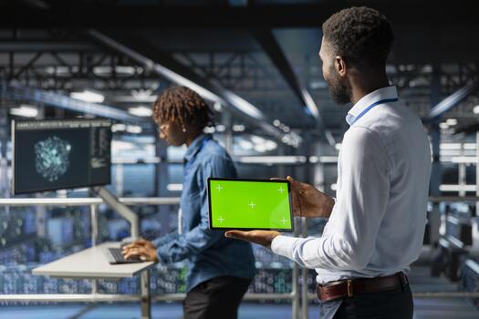 africano americano ingeniero usos croma llave monitor en tableta en datos centro, analizando actuación salidas en pie en industrial plataforma. servidor cubo Ingenieria ai configuraciones foto