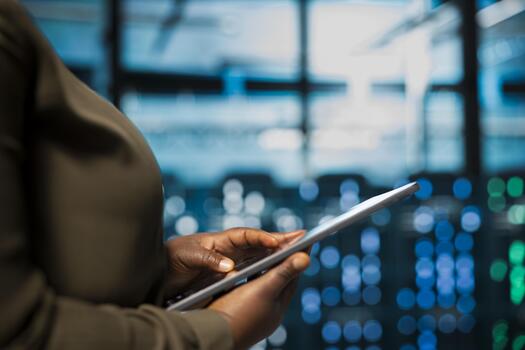 Close up of software developer using tablet in data center to track metrics of gear used to host websites. Server hub IT professional upgrading capacity of storage rigs running companies databases photo