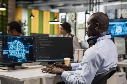 IT employee in office automating repetitive business workflows using artificial intelligence tech on computer. African american man refining deep learning computational models with PC photo
