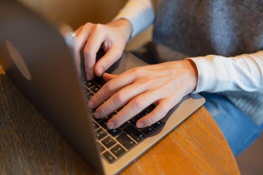 Closeup of hands typing on a laptop keyboard in a cozy cafe environment, representing concepts of remote work, productivity, digital communication, creative workflow and modern workspace lifestyle. photo