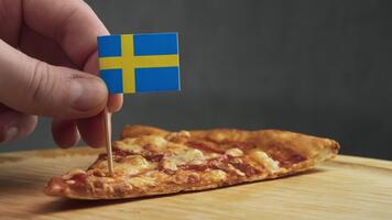 stänga upp av pizza skiva på trä- yta med svenska flagga, ram fokuserar på nordic mejeri ost, lokal- vete skorpa och scandinavian stil presentation. närbild video