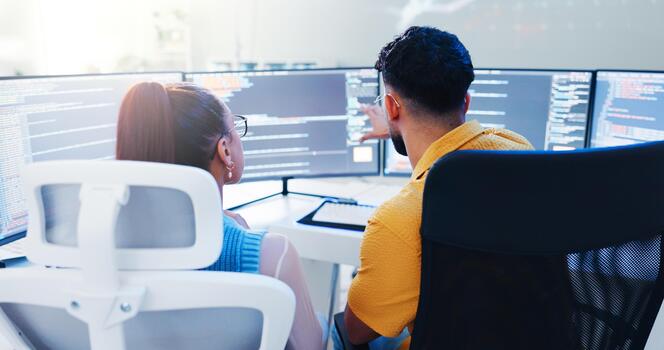 Two people coding on multiple screens photo