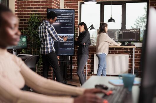 Diverse tech engineers use binary code to program firewall encryption and develop network security software on a shared server system. photo