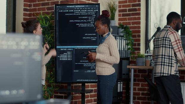 software ontwikkelaar vergelijkt bron code fouten Aan een muur scherm met een digitaal tablet, Verbinden debuggen, binnen een programmeur kantoor instelling. video