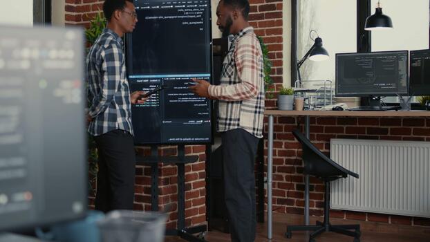 programvara utveckling team studier vägg skärm koda under en felsökning session med en digital läsplatta, länkning fel kontroll, medan jämförande programmering resultat. video