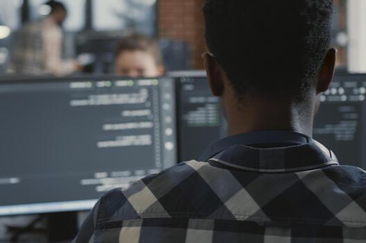 Programmer Coding on Laptop with Multiple Screens in a software development office, showing programmers collaborating on source code, algorithms and data coding workflow. photo
