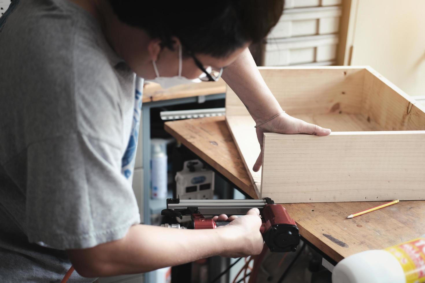 falegnameria dell'imprenditore che tiene una graffatrice per assemblare i pezzi di legno come ordinato dal cliente. foto