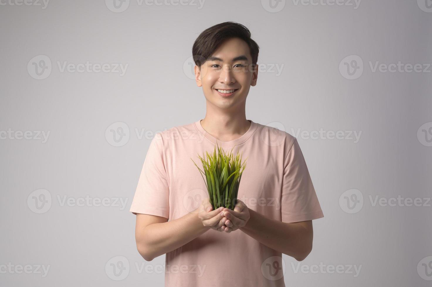 giovane uomo sorridente azienda albero su sfondo bianco studio, salvare il concetto di terra foto