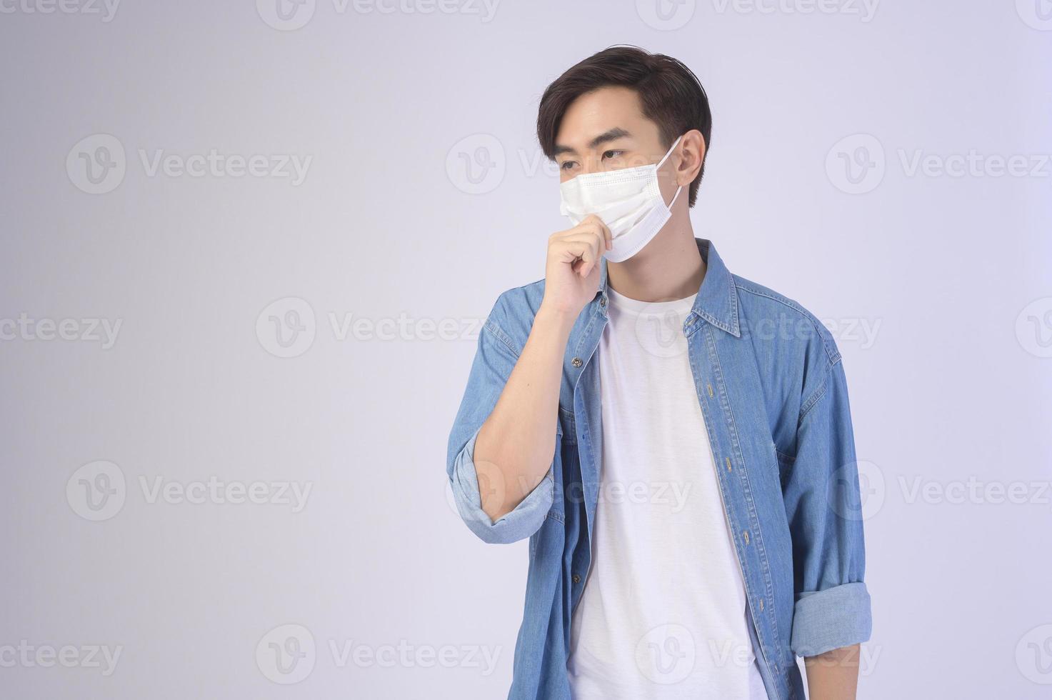 giovane uomo asiatico che indossa una maschera protettiva su sfondo bianco studio, viaggi di sicurezza, nuova normalità, distanza sociale, covid19 e concetto di pandemia. foto