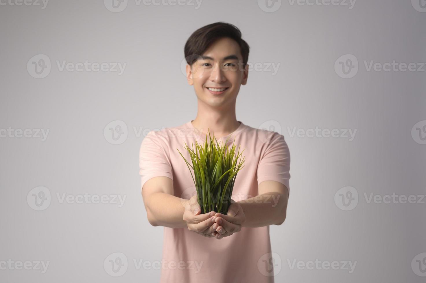 giovane uomo sorridente azienda albero su sfondo bianco studio, salvare il concetto di terra foto