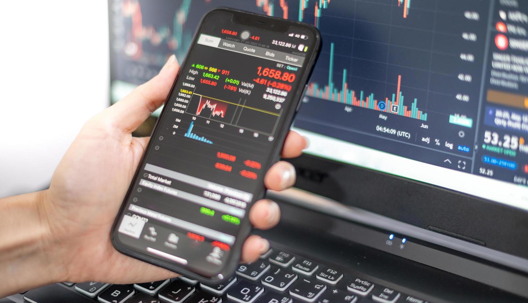 analista broker investitore femminile che tiene in mano uno smartphone analizzando i grafici di trading del mercato azionario indicizzando i dati che controllano il prezzo utilizzando l'applicazione mobile di borsa del mercato azionario. foto