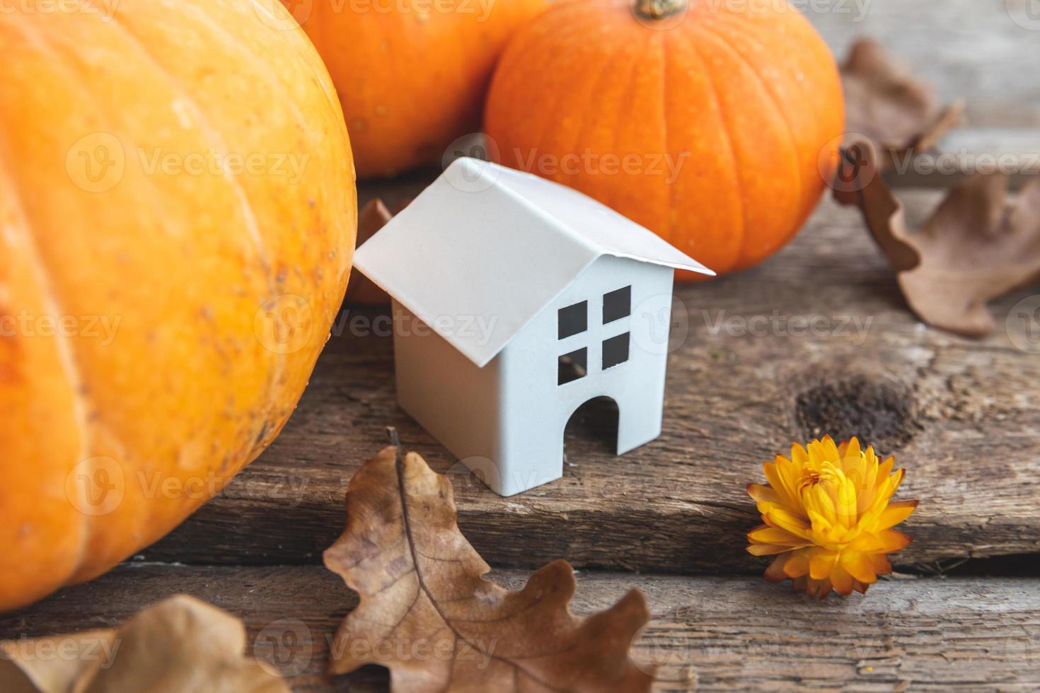 sfondo autunnale. casa del giocattolo e zucca su fondo di legno. banner di ringraziamento copia spazio. umore hygge, concetto di cambio di stagione. ciao autunno con la festa di Halloween in famiglia. foto