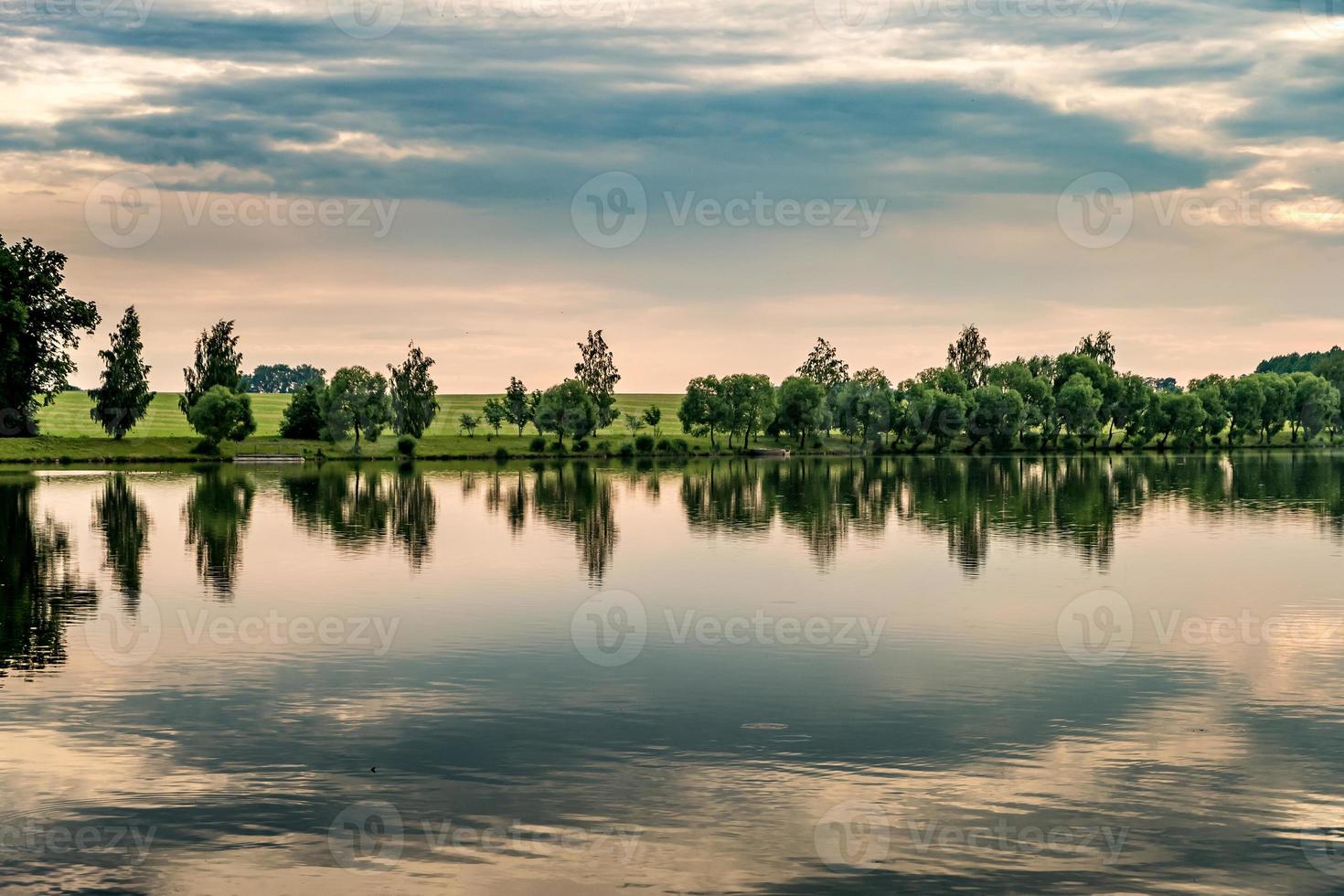 riflesso di alberi in un lago d'acqua in una tranquilla sera d'estate foto