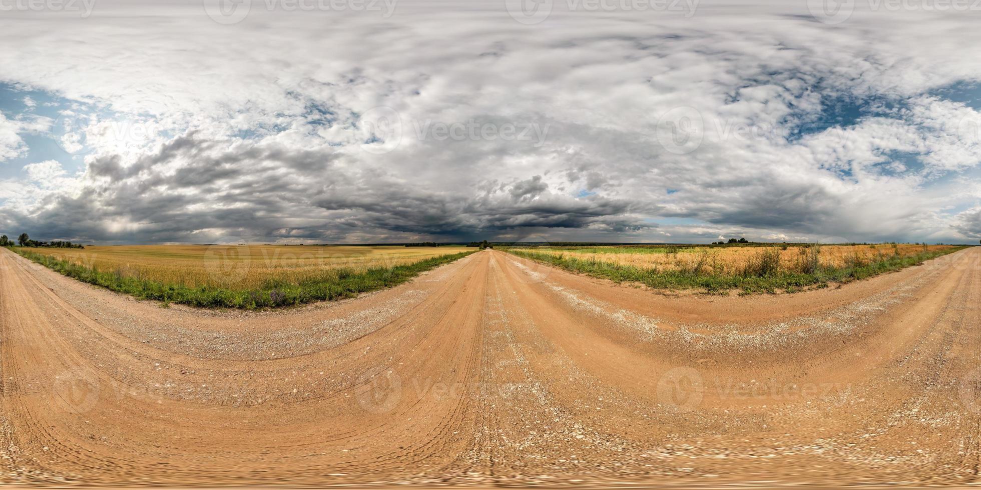 panorama hdri sferico completo senza soluzione di continuità vista a 360 gradi su strada sterrata tra i campi con nuvole fantastiche prima della tempesta in proiezione equirettangolare, pronto per contenuti di realtà virtuale vr ar foto