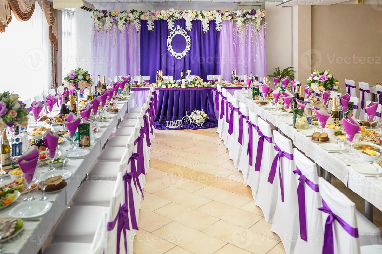 bellissimi fiori su un'elegante tavola da pranzo nel giorno del matrimonio. decorazioni servite sulla tavola festiva su sfondo viola foto