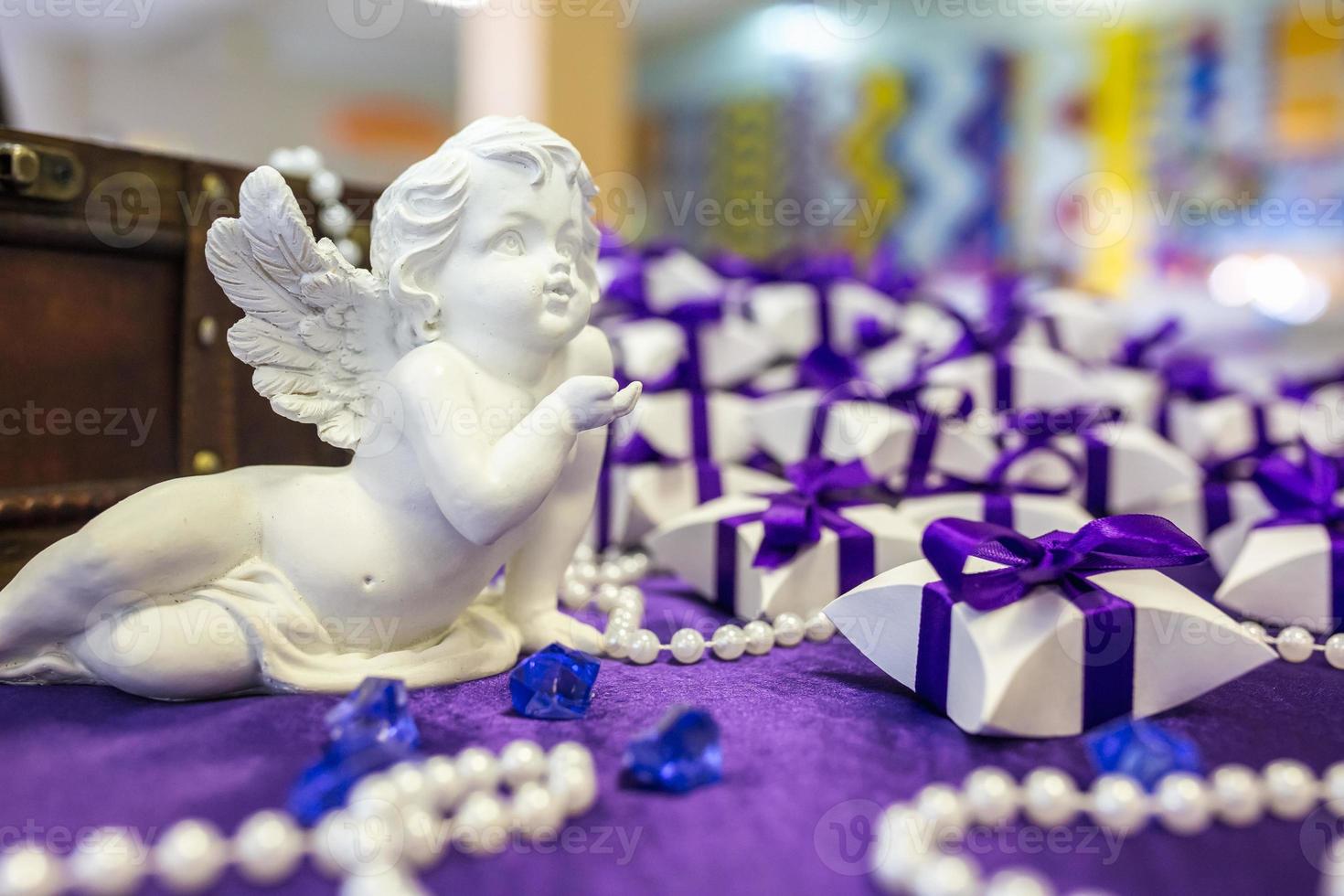 angelo in ceramica sul tavolo con tovaglia viola e piccoli regali per gli invitati degli sposi novelli foto