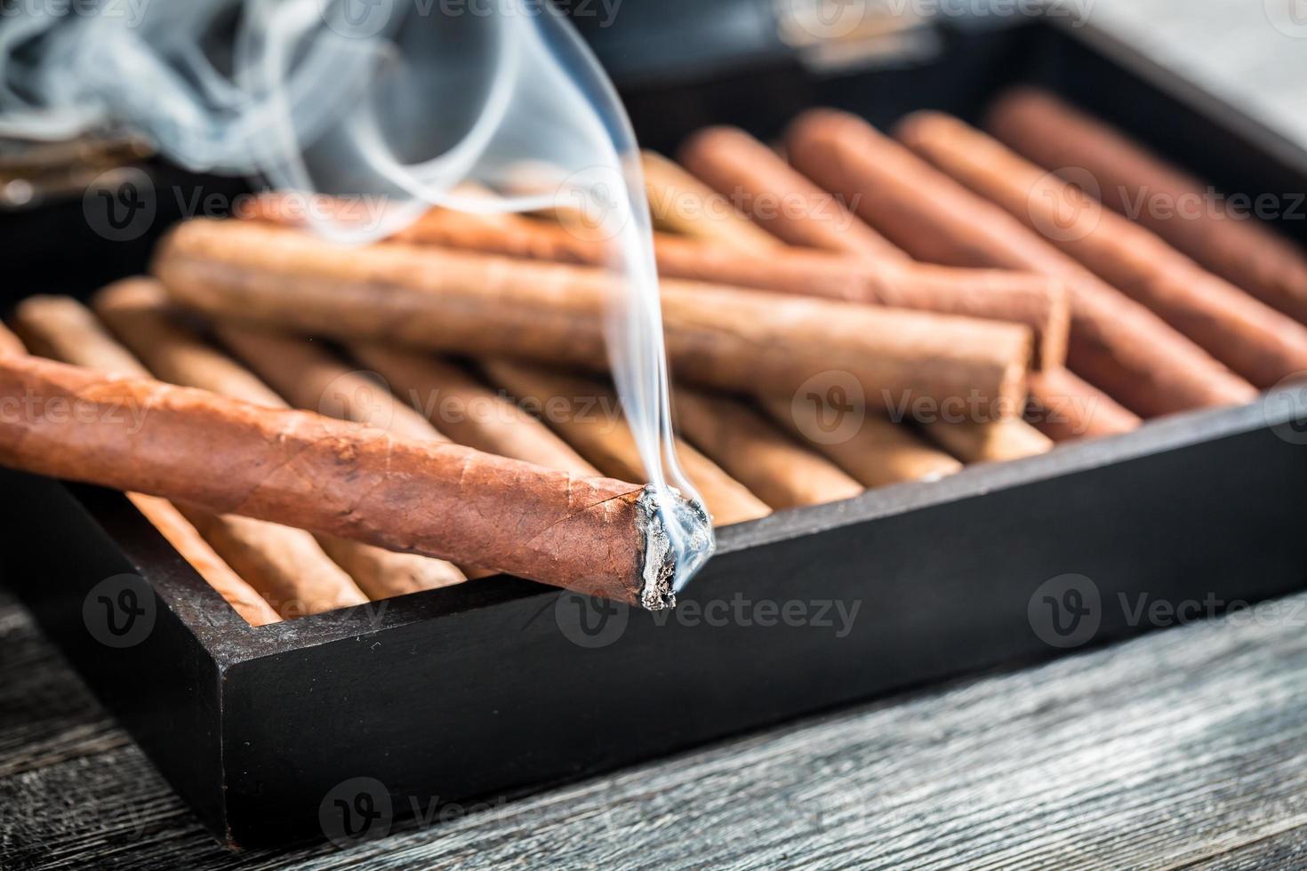 primo piano di bruciare sigaro su humidor in legno foto