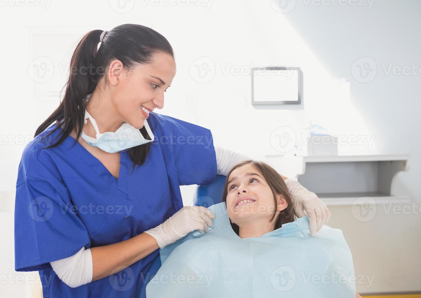 dentista pediatrico che mette sul suo giovane paziente gli scrub foto