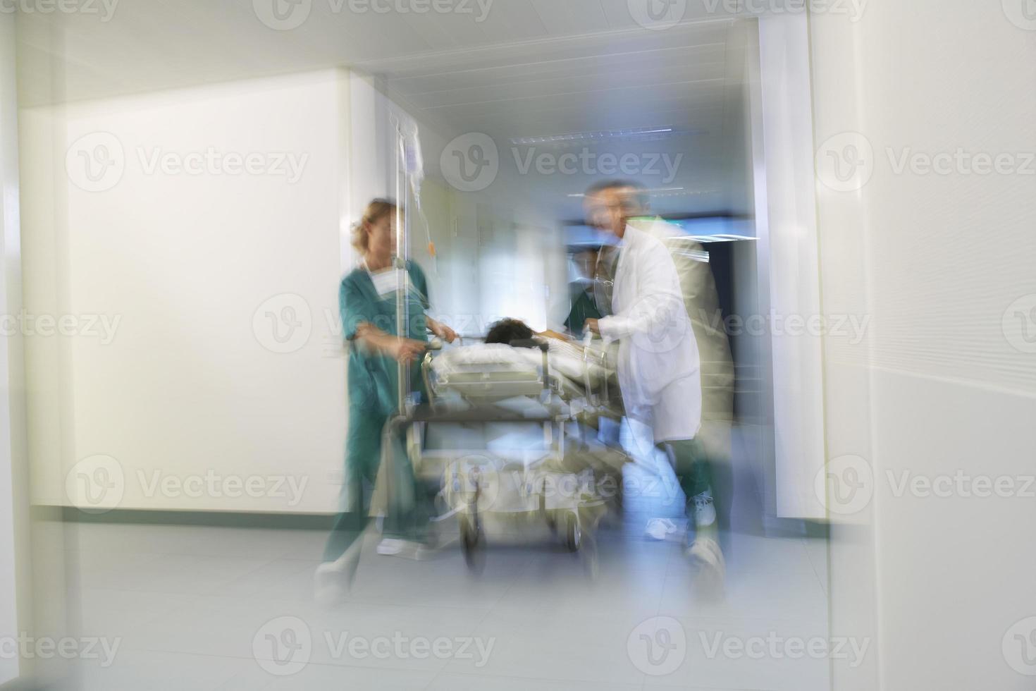 medici che spostano il paziente sulla barella attraverso il corridoio dell'ospedale foto