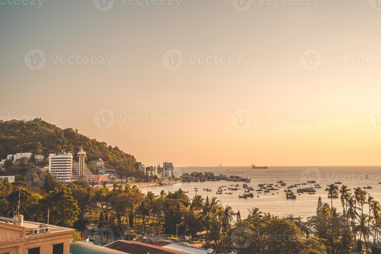 vista aerea della città di vung tau con un bel tramonto e tante barche. vista panoramica costiera di vung tau dall'alto, con onde, costa, strade, palme da cocco e montagna tao phung in vietnam. foto