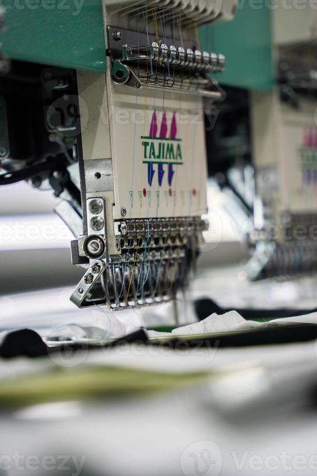 macchina da cucire moderna e automatica ad alta tecnologia per il processo di produzione di abbigliamento tessile o abbigliamento in ambito industriale. industria tessile digitale. ricamo computerizzato. foto